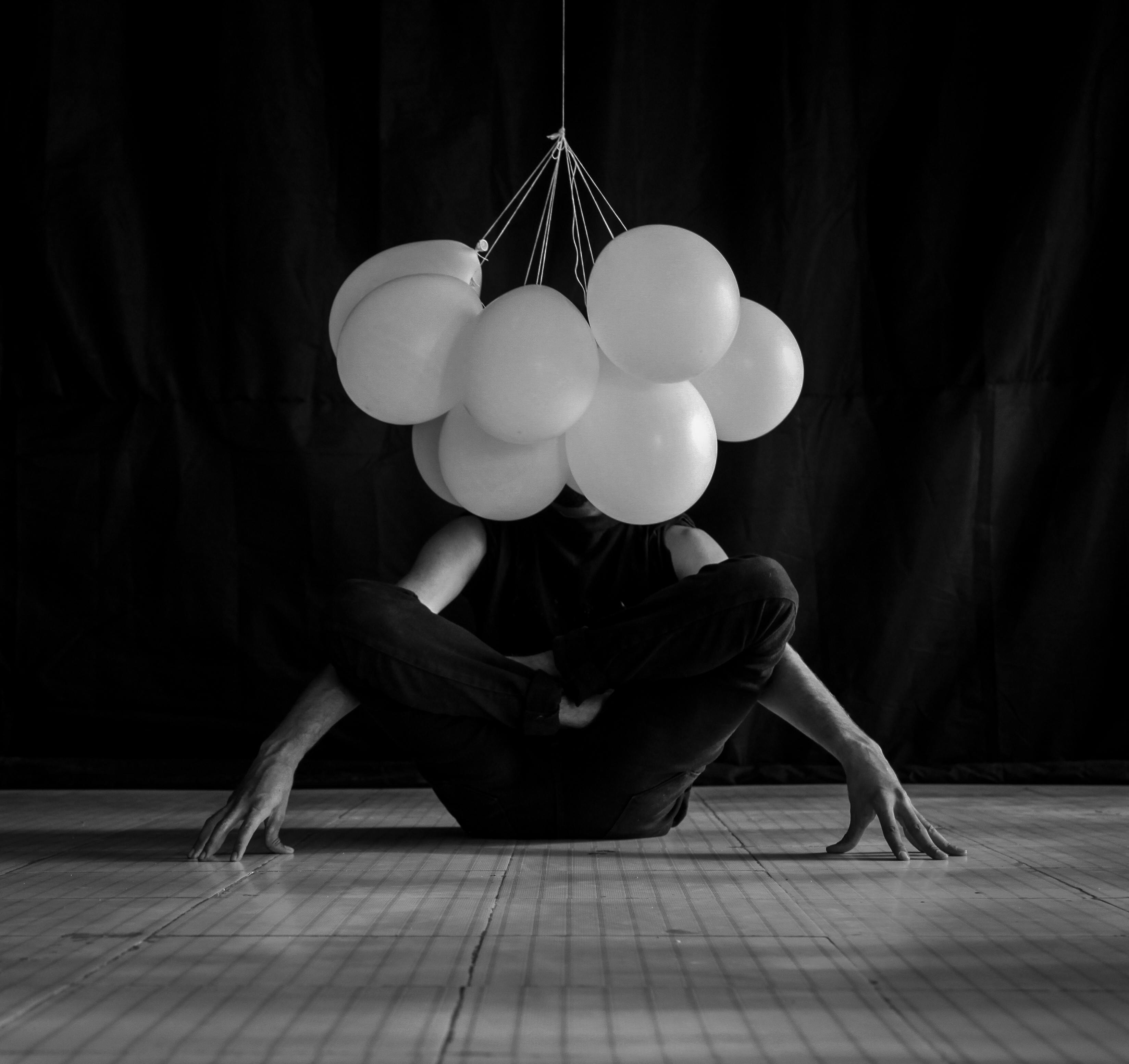 Artistic dance performance with balloons in a grayscale setting.