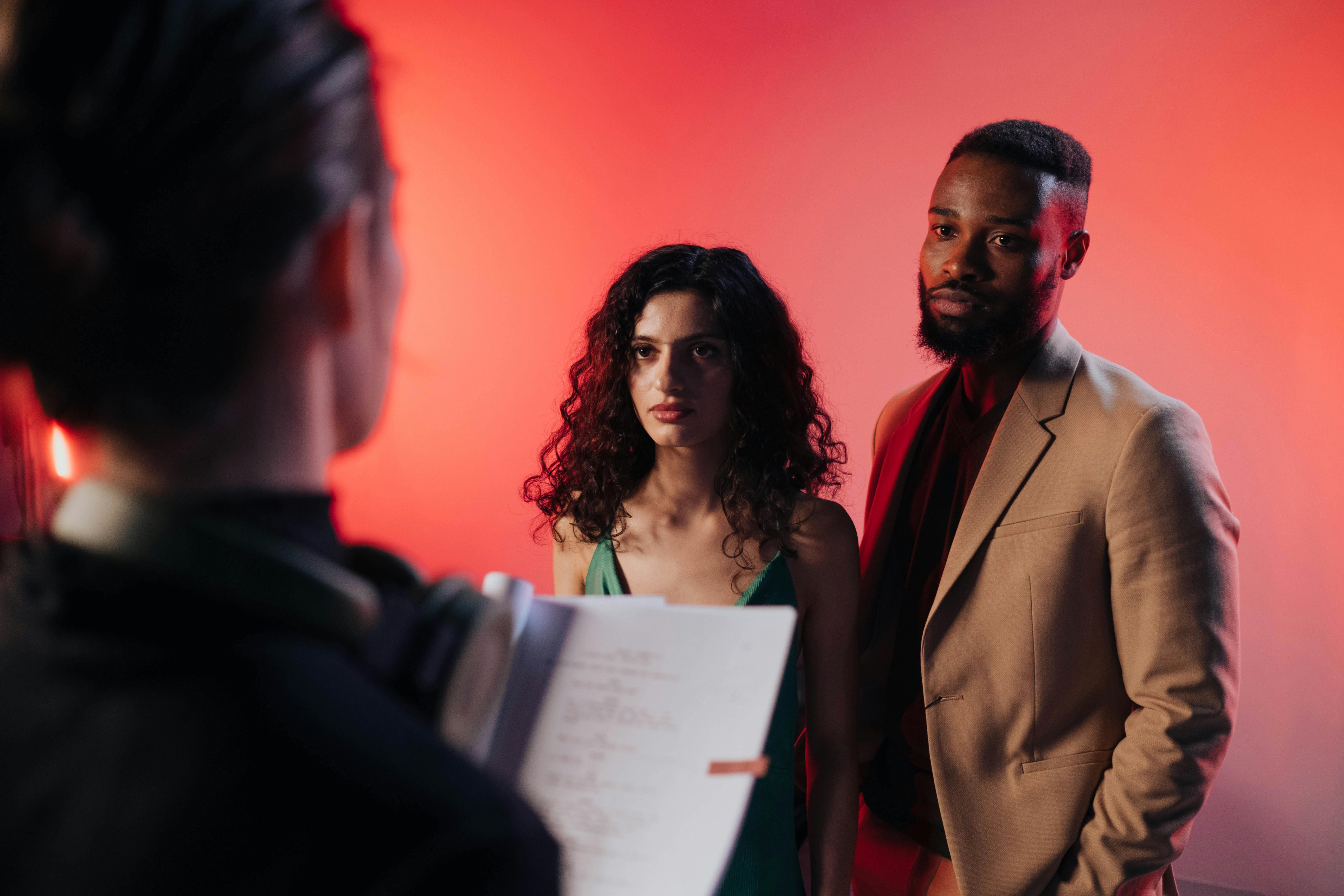 Couple reading script in a studio with warm lighting for film or theater production.